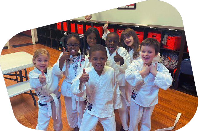 a group of young children in karate uniforms are giving a thumbs up .