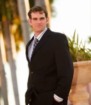 A smiling doctor in a lab coat with a stethoscope around his neck.