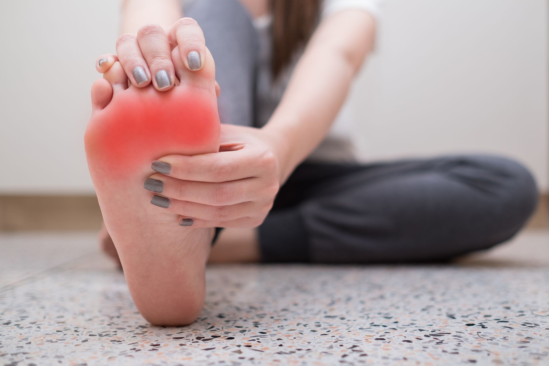 Person holding foot, which is highlighted with red, suggesting pain.