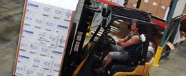 A man is driving a forklift in a warehouse.