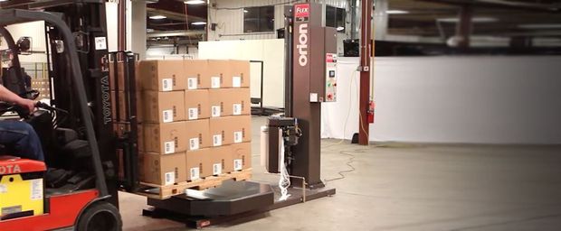 A man is driving a forklift in a warehouse with boxes on it.