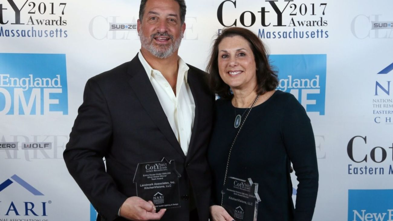 A man and woman smiling, holding awards, at the 