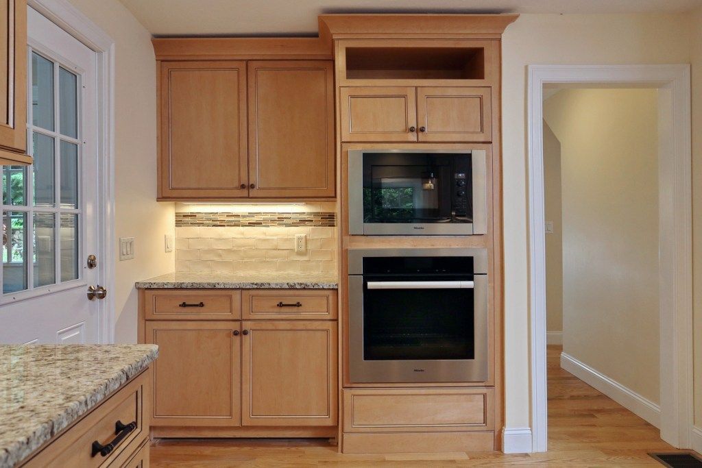 Kitchen with light wood cabinets, built-in oven and microwave, granite countertops.