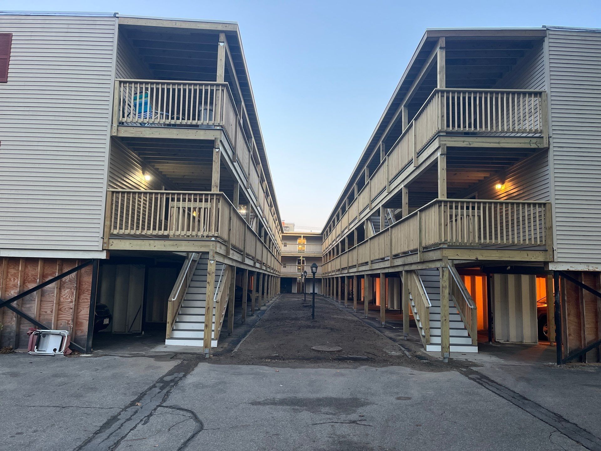 Two-story apartment buildings with outdoor staircases face each other, forming a narrow alley.