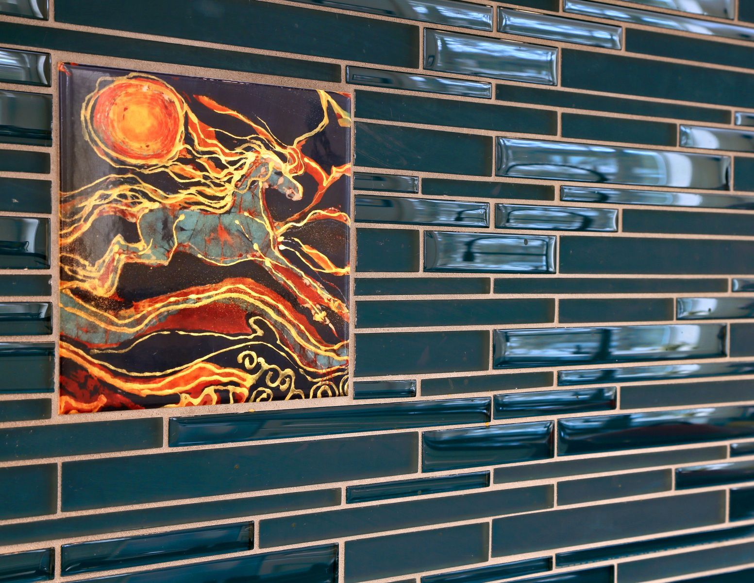Tile backsplash with inset art of a horse under a fiery sun; dark teal and orange hues.