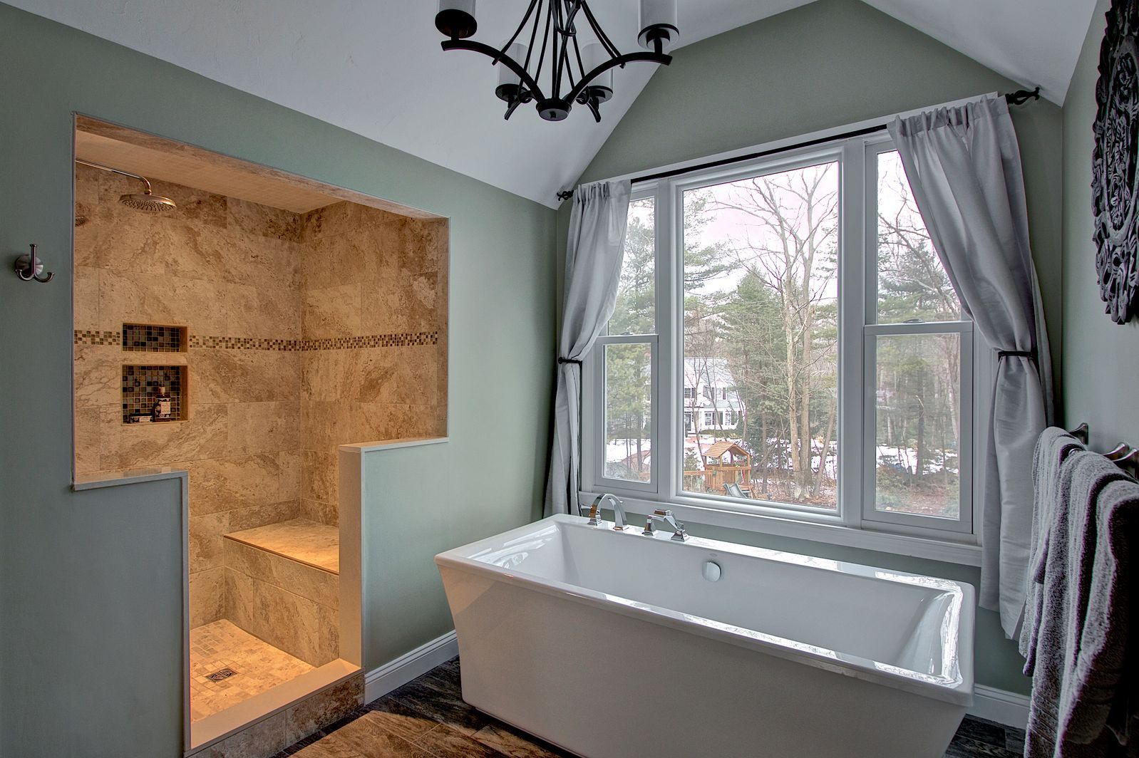 Bathroom with walk-in shower, freestanding tub, window with curtains, and chandelier.