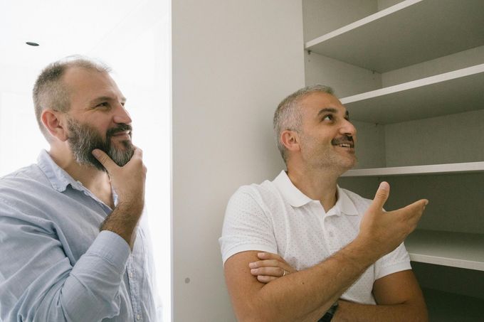Two men looking at empty shelves; one has a beard, the other gestures with his hand.