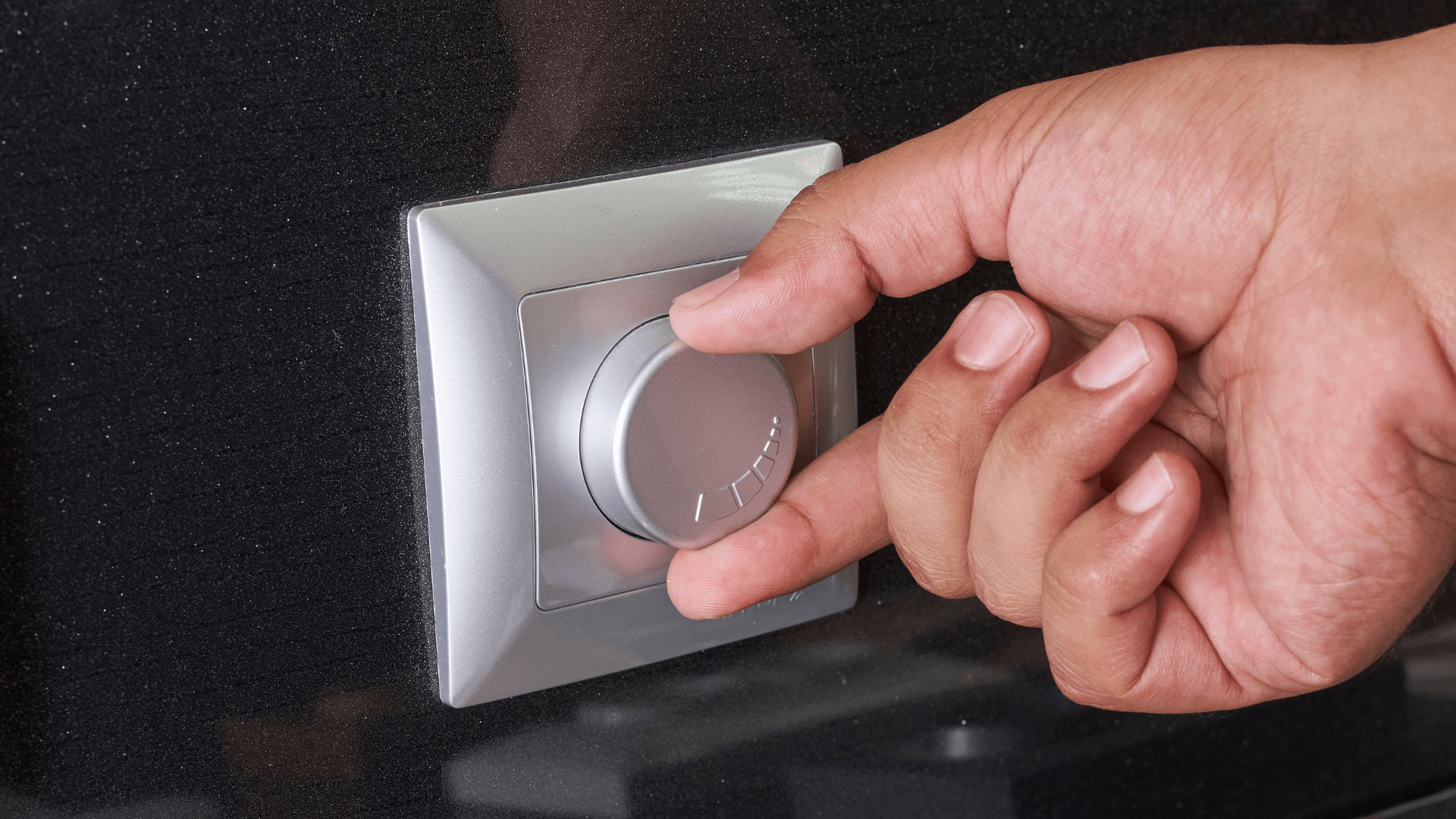 A person is adjusting a light switch with their finger.