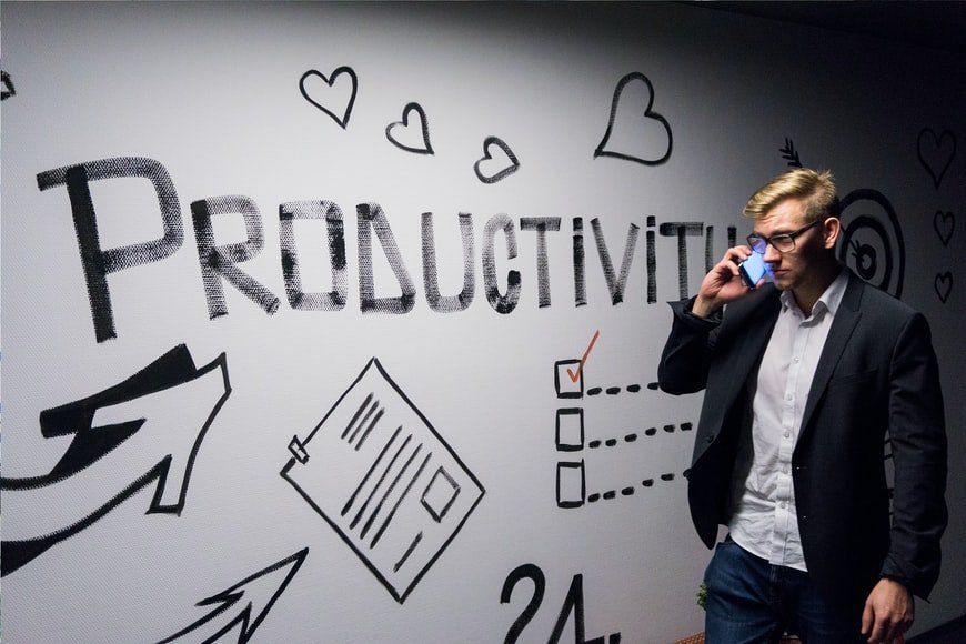 A man talking on a cell phone in front of a wall that says productivity