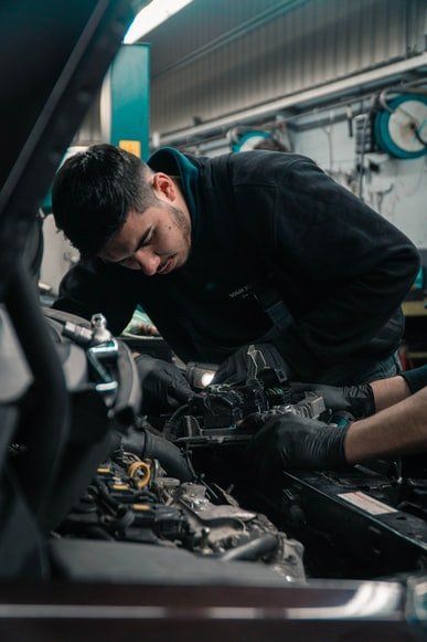 A man is working on the engine of a car in a garage.