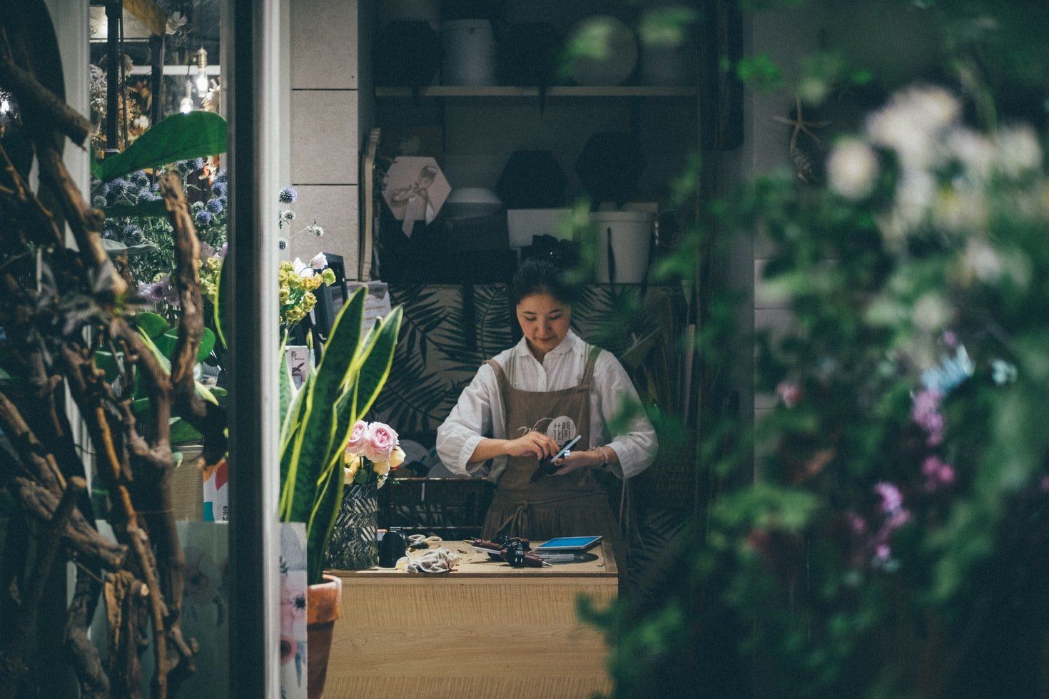 A woman is sitting at a counter in a flower shop.