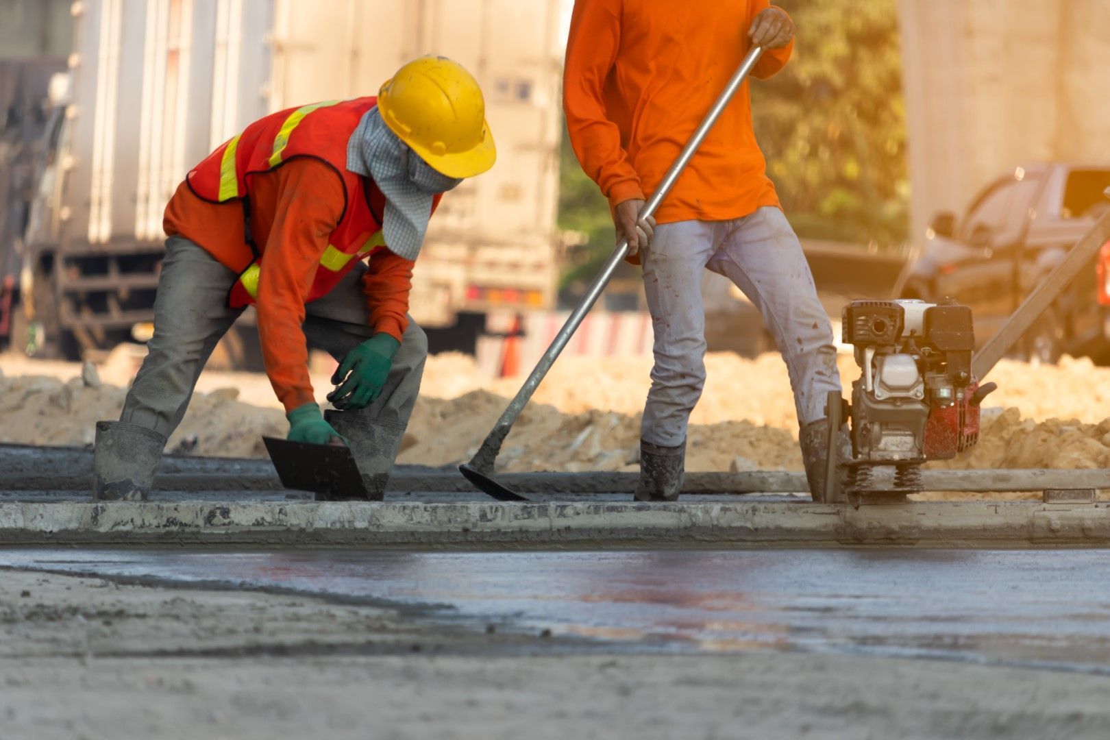 A couple of construction workers are working on a road.