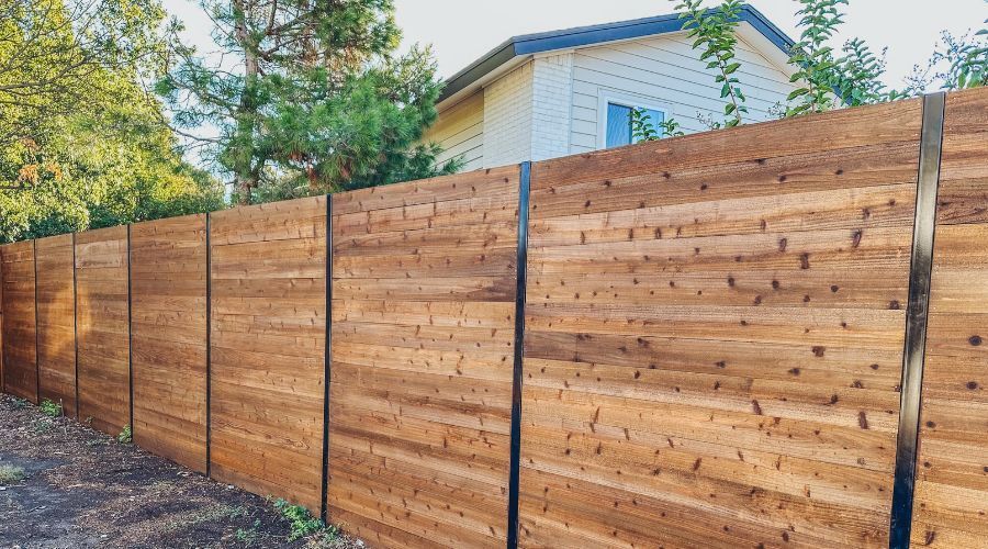 Modern horizontal wood privacy fence with sleek black metal posts installed at a residential propert