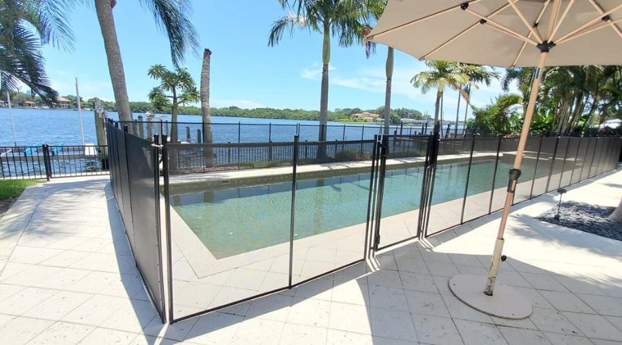 Black mesh safety fence installed around a waterfront swimming pool in St. Petersburg, FL.