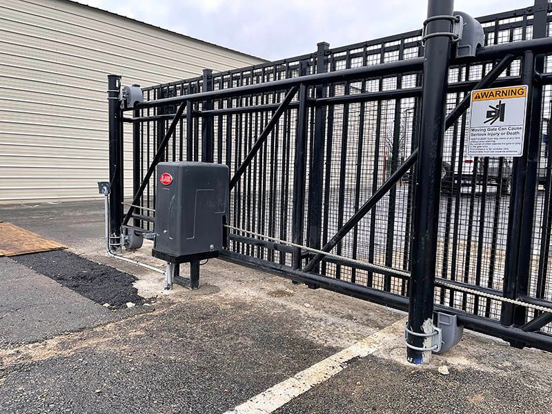 A black sliding gate with a box on the side of it.