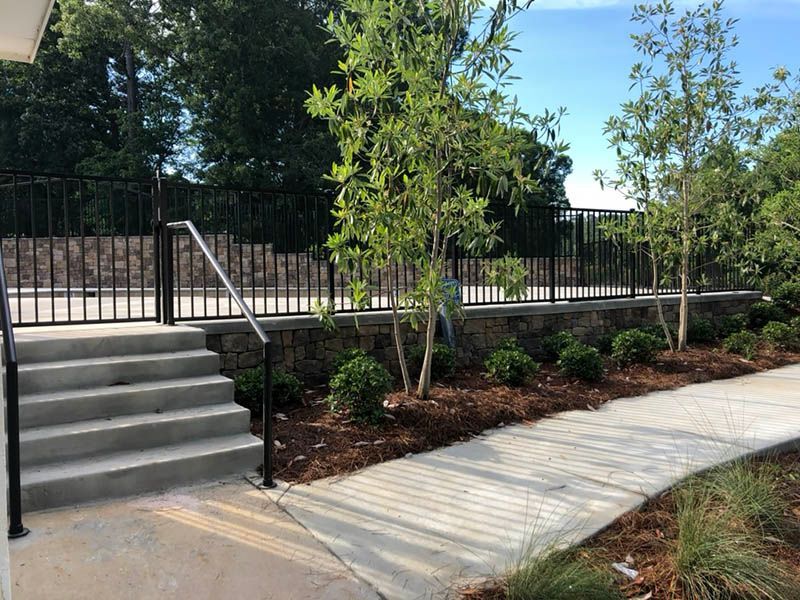 A concrete walkway with stairs and a fence in the background.