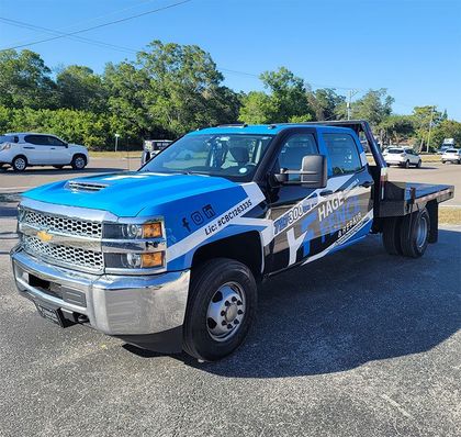 A blue tow truck is parked on the side of the road.