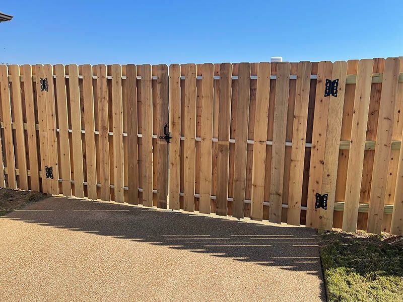 A wooden fence with a gate and a blue sky in the background