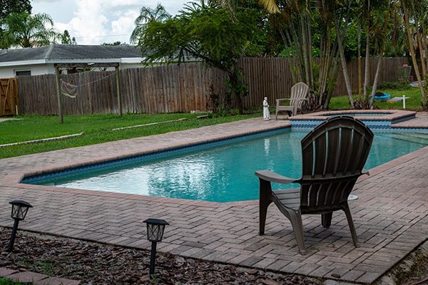 A chair is sitting next to a swimming pool in a backyard.