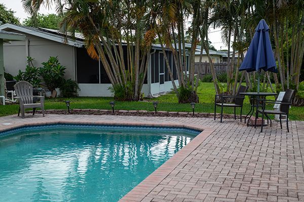 A swimming pool with chairs and umbrellas in front of a house