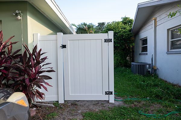 A white gate is in the backyard of a house.
