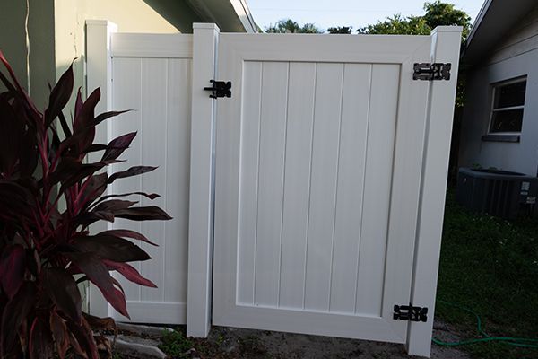 A white fence with a gate in front of a house