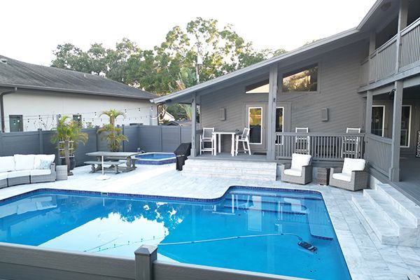 A large swimming pool is in the backyard of a house.