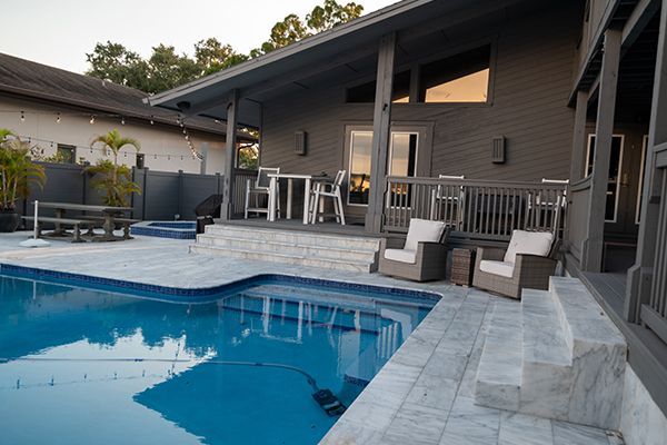 There is a large swimming pool in the backyard of a house.