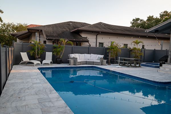 There is a large swimming pool in the backyard of a house.