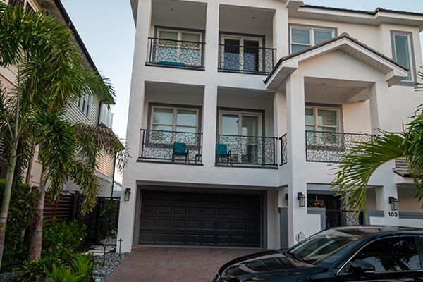 A white house with a black car parked in front of it