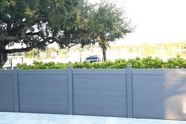 A gray fence with a tree in the background.