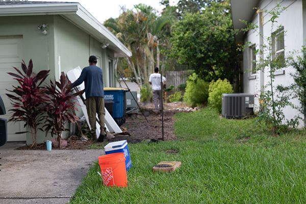 Two men are working in the backyard of a house