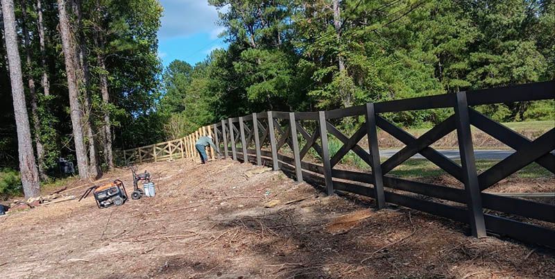 A wooden fence is being built in the middle of a dirt field.