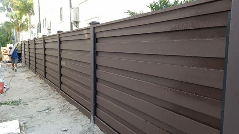 A brown wooden fence is being built in front of a house.