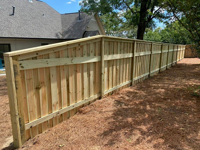 A wooden fence is in the backyard of a house.