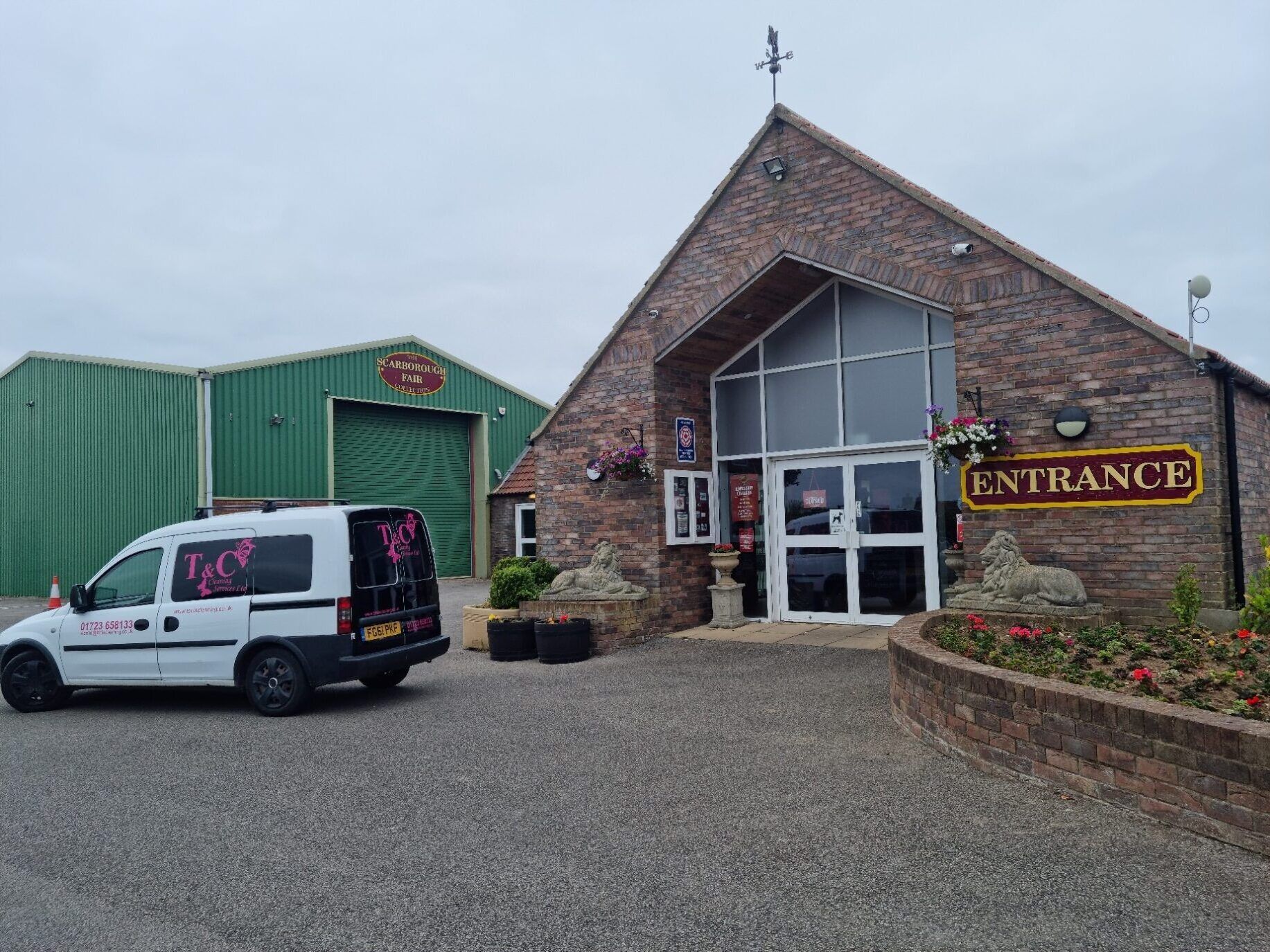 A white van is parked in front of a brick building.