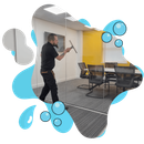 A man is cleaning a glass wall in a conference room.