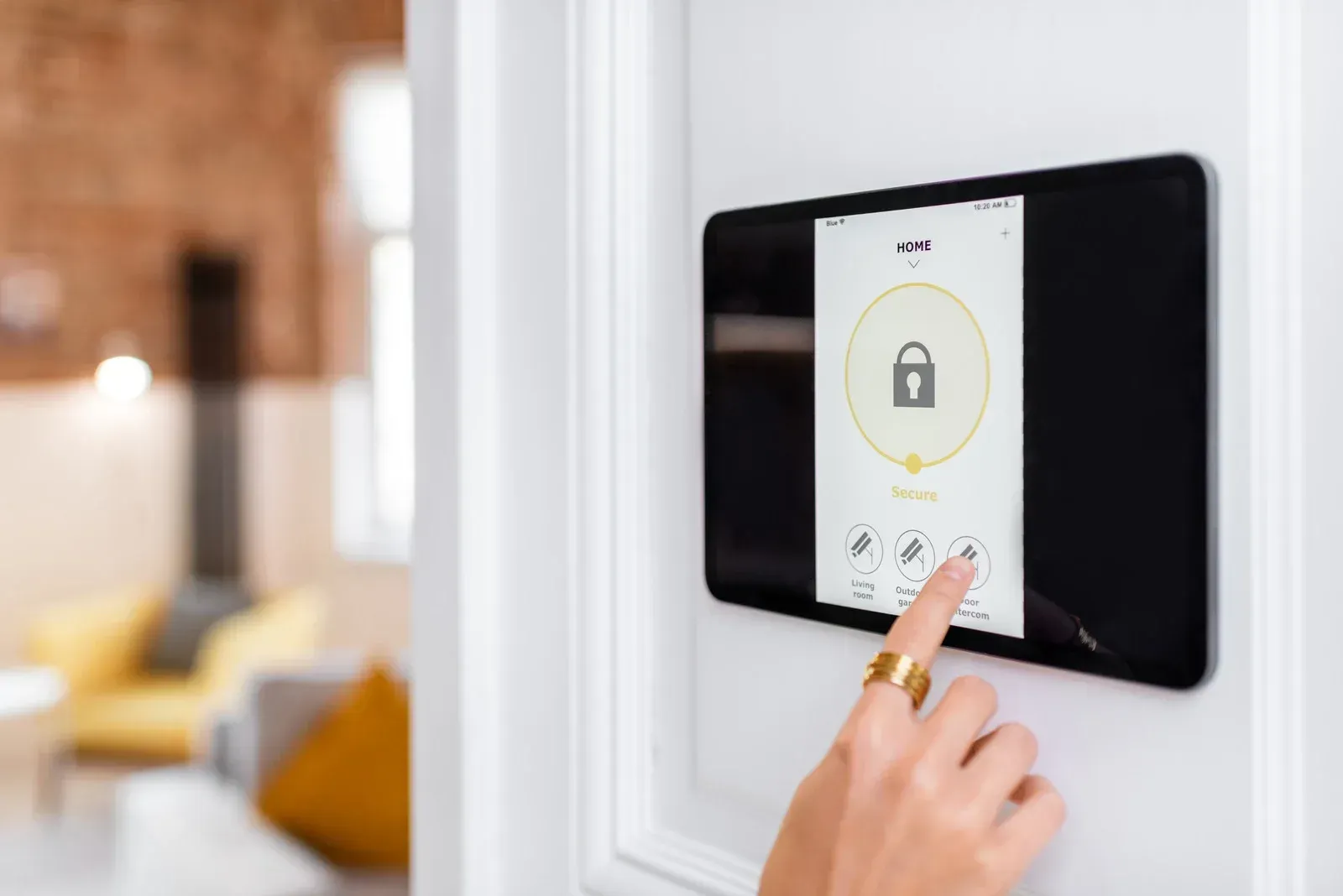 Person's hand touching a smart home security system's touchscreen, displaying a lock icon.