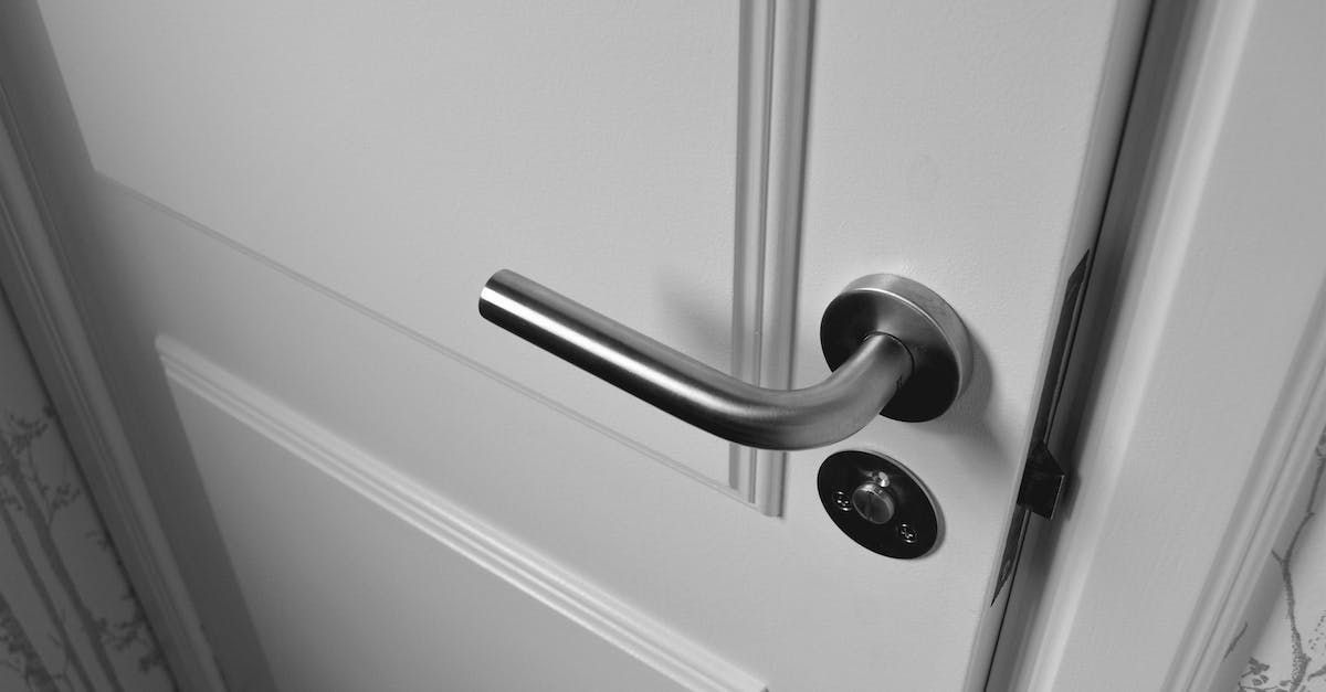 A close-up of a white door with a silver handle and a keyhole.