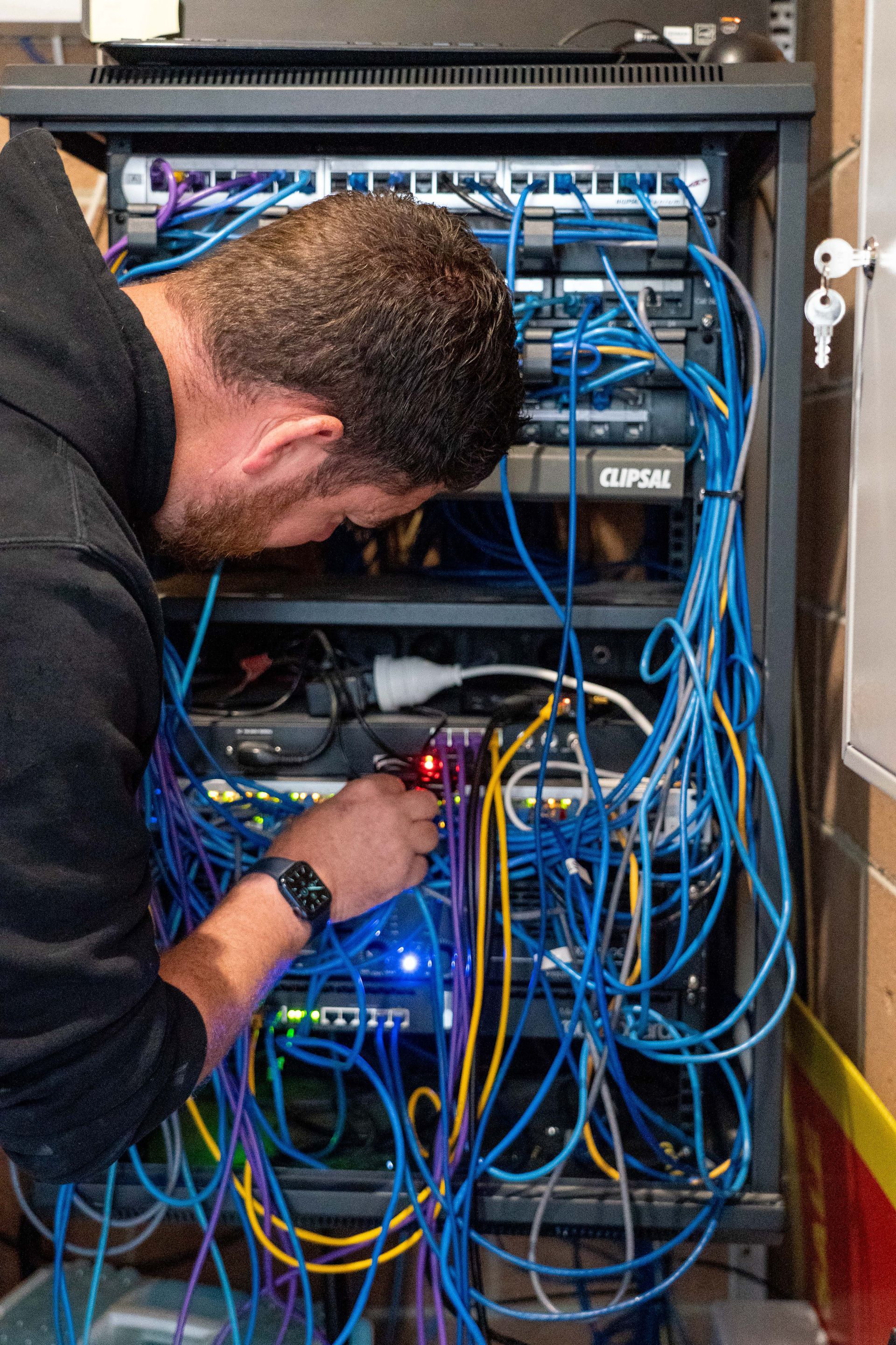 Electrician using a clamp meter to test wires in a control panel.