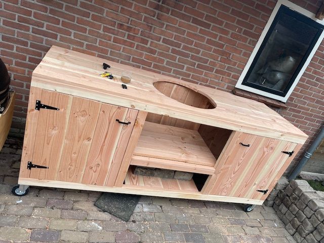 Houten barbecuekar met kastdeuren en ronde opening, op wielen.