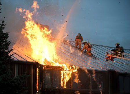 A group of firefighters are fighting a fire on the roof of a building.