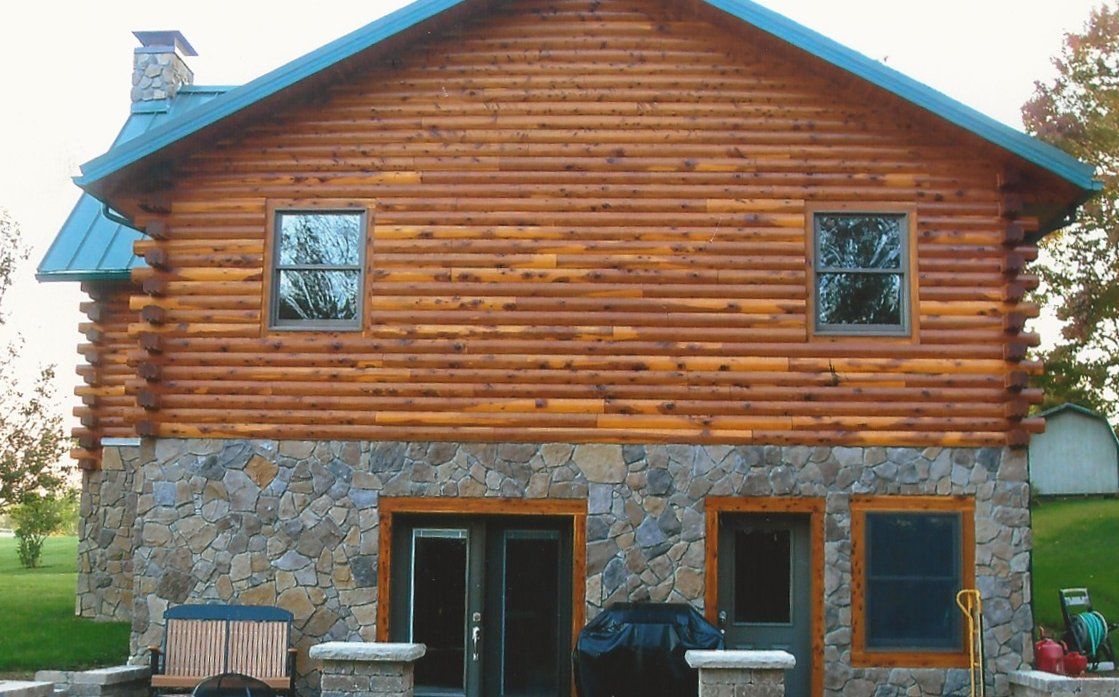 A log cabin with a stone wall and a blue roof