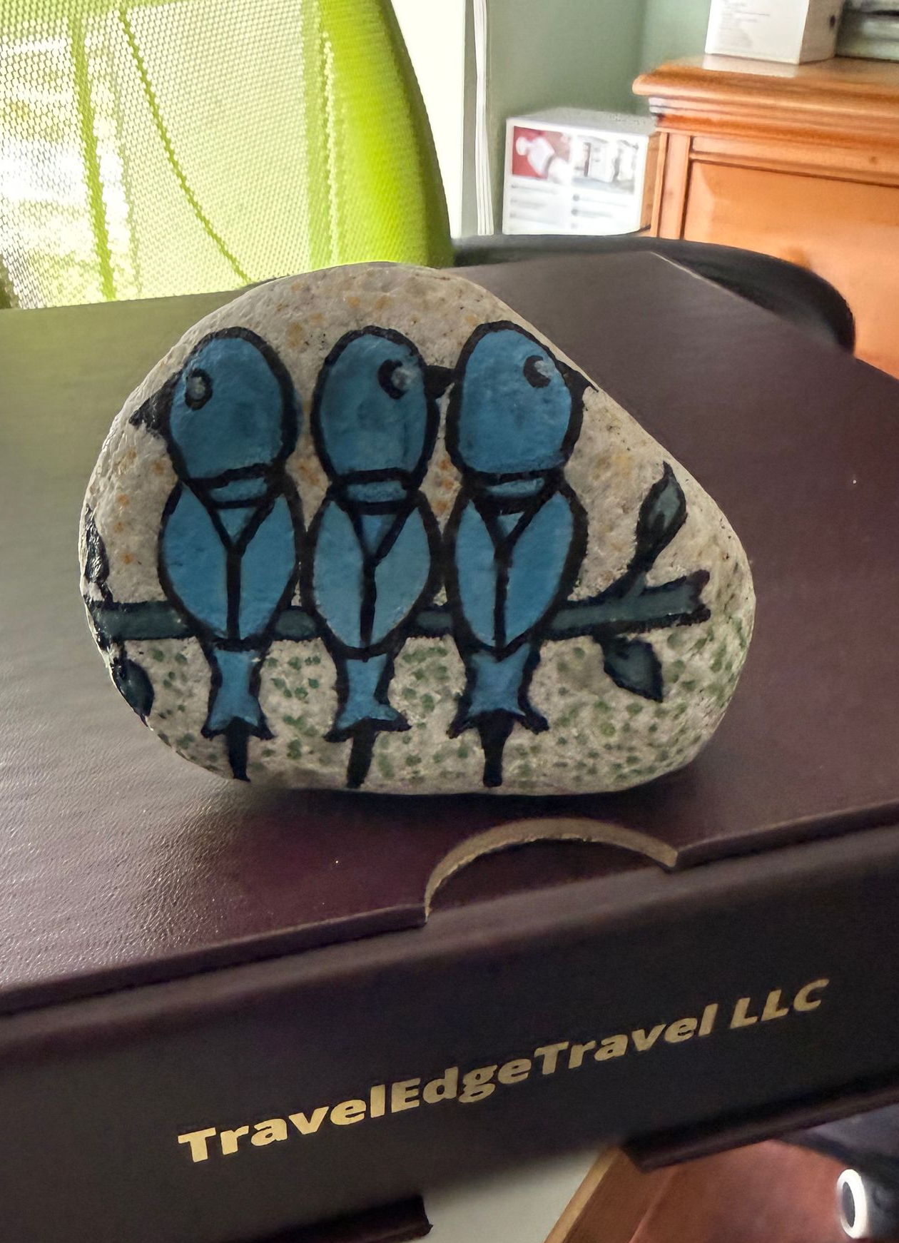 Painted rock with three blue birds perched on a branch.