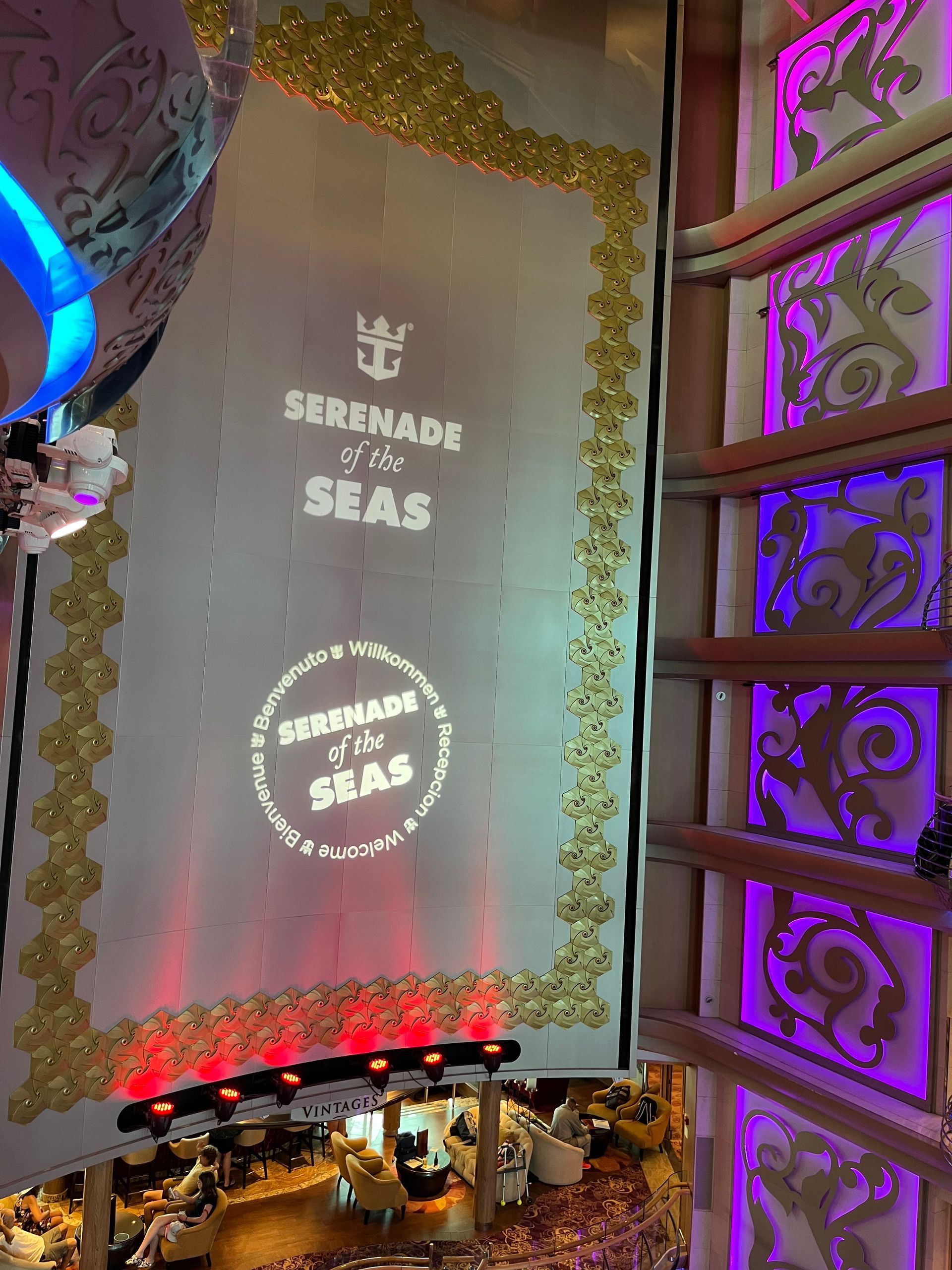 Royal Caribbean's Serenade of the Seas cruise ship interior with projected logos and ornate gold trim.