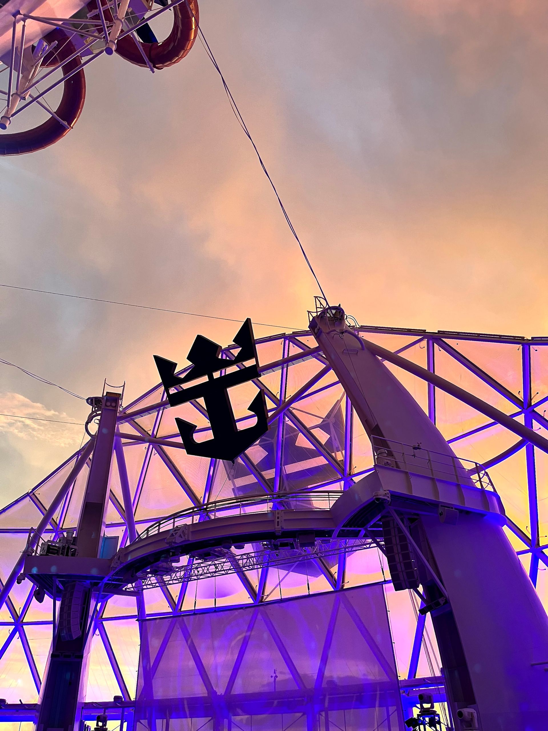 Anchor emblem on cruise ship roof structure; dusk sky.