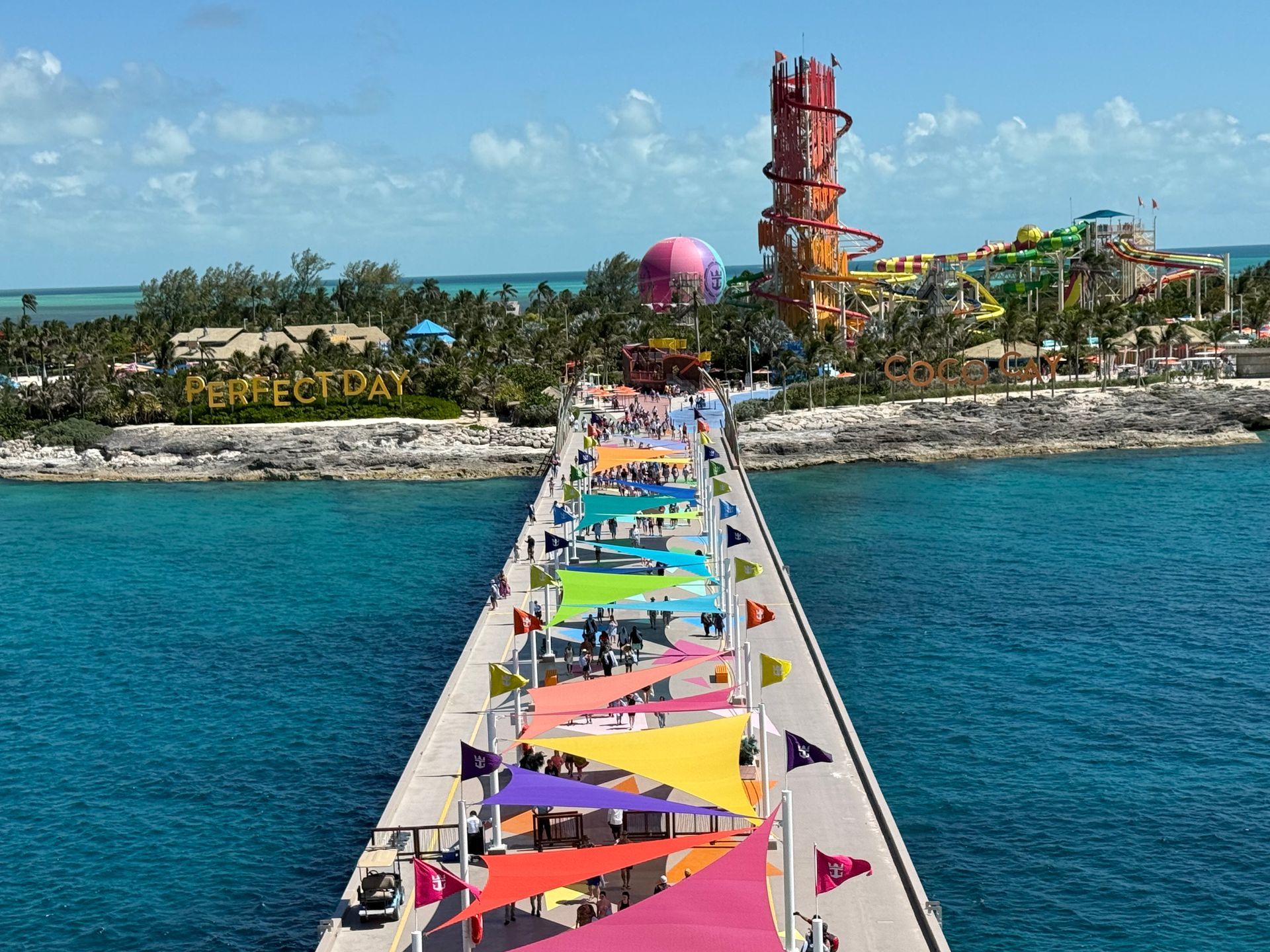 Pier leading to Perfect Day island with colorful canopies and water park.