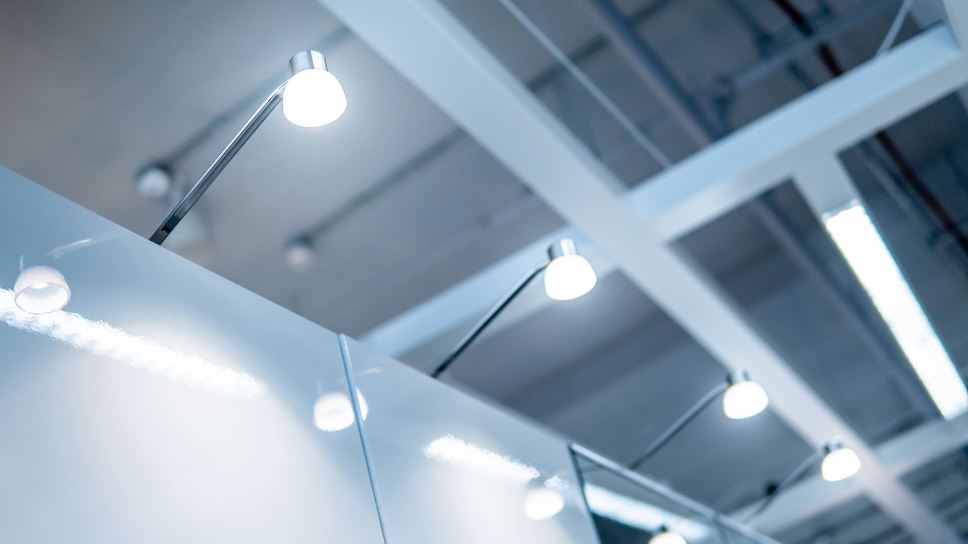 Ceiling-mounted spotlights illuminating a modern indoor space with white panels
