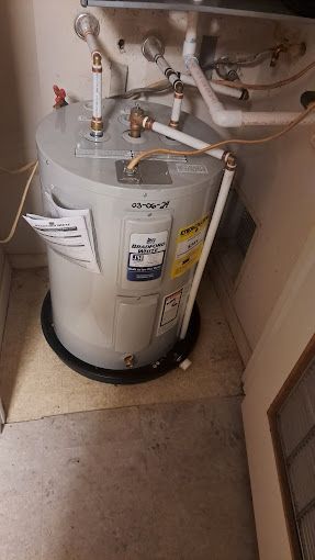 A water heater is sitting on the floor in a room.