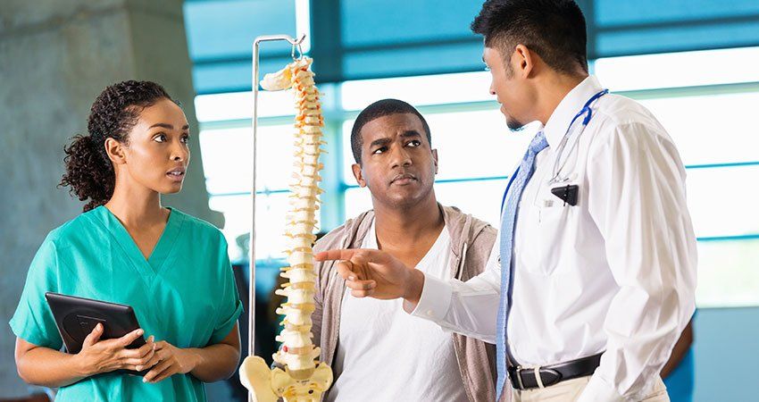 doctors showing patient a model spine